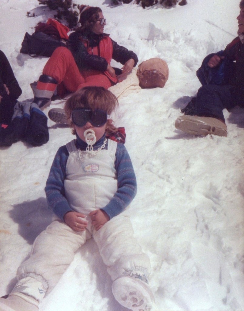 Mami de pequeña sentada en la nieve con chupete